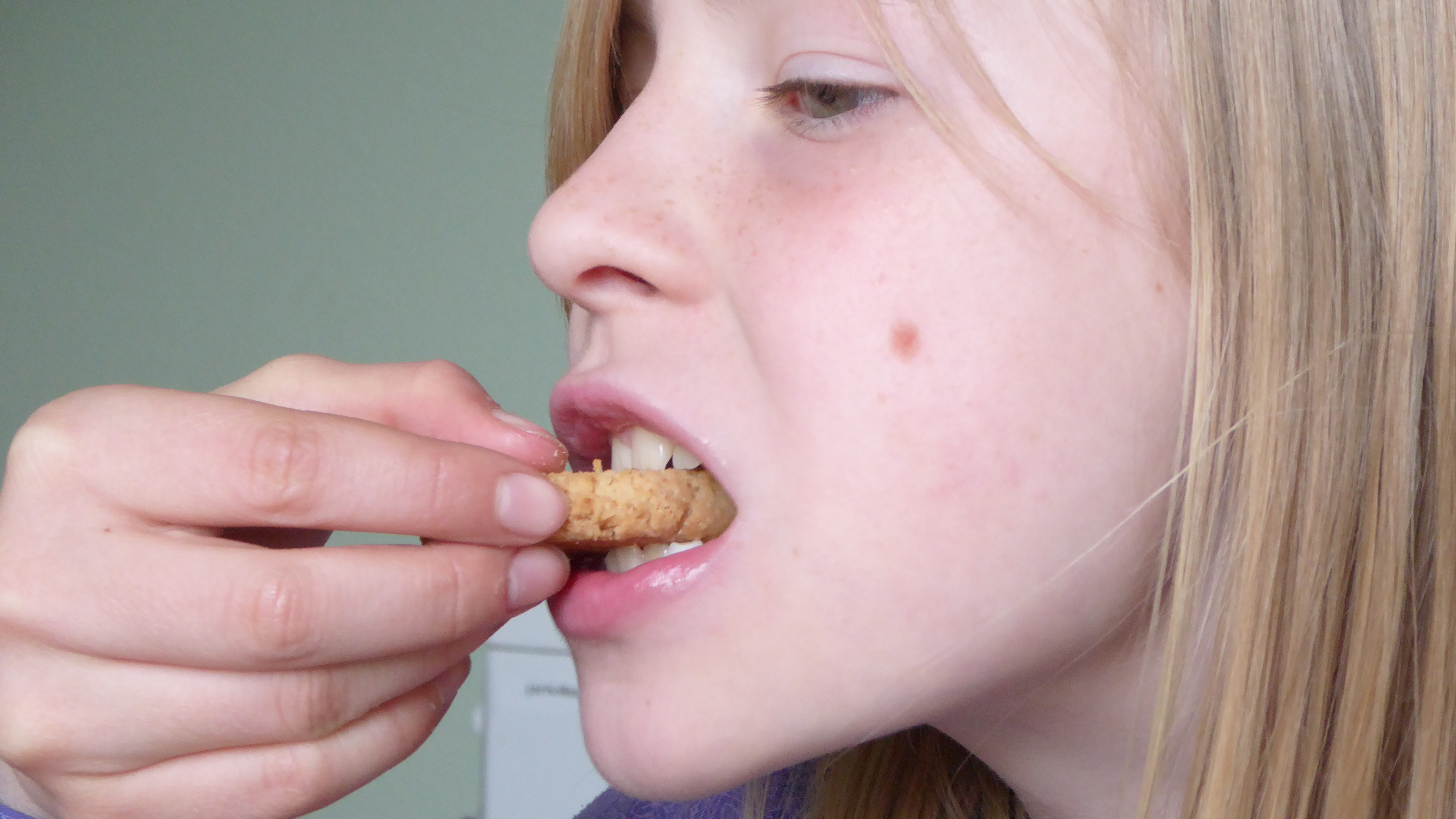 Привкус рвоты во рту. Человек ест печенье. Девушка ест печенье. Жующий рот.
