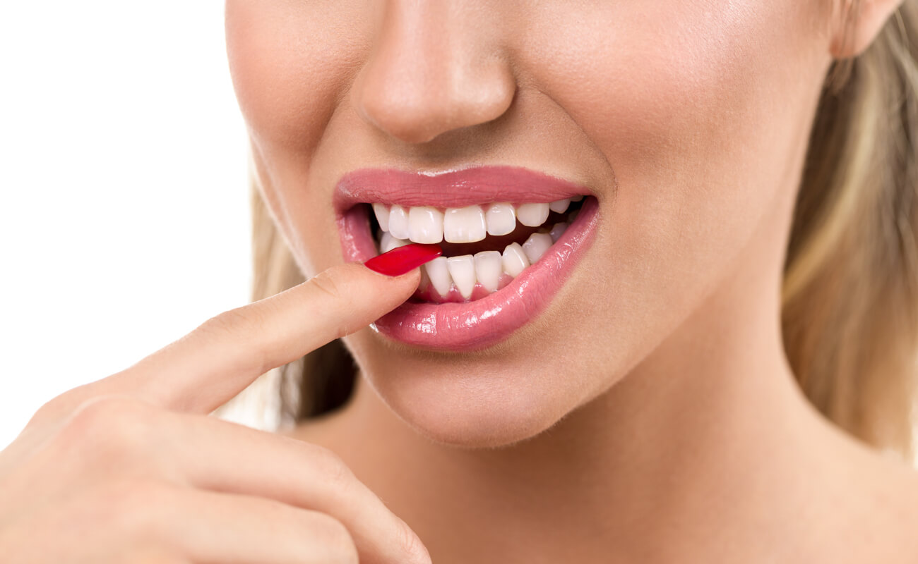 Фото причины стираемсоти зубов – девушка грызущая ногти